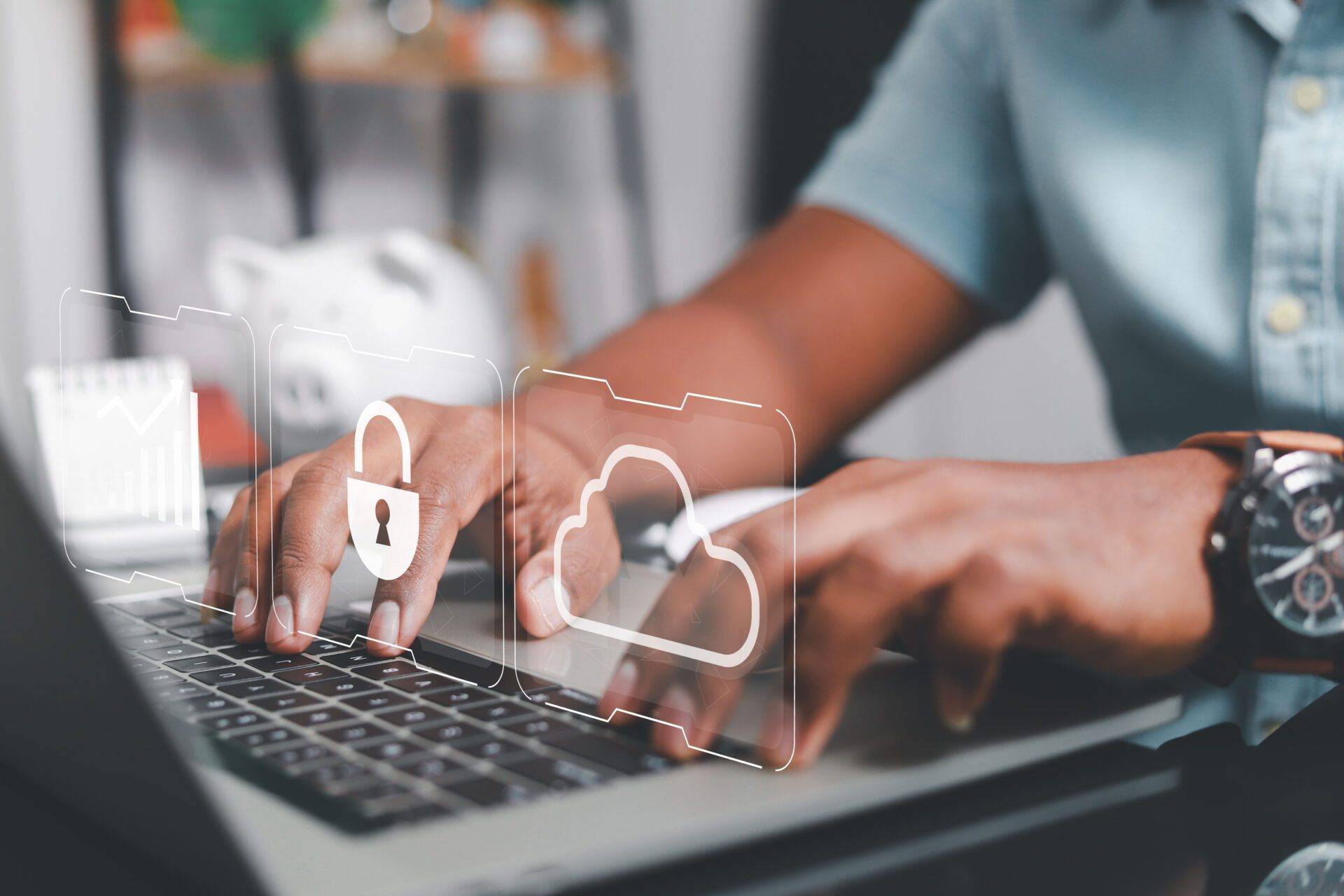 Person skriver på laptop med digitala ikoner för säkerhet och molnlagring projicerade ovanför tangentbordet.