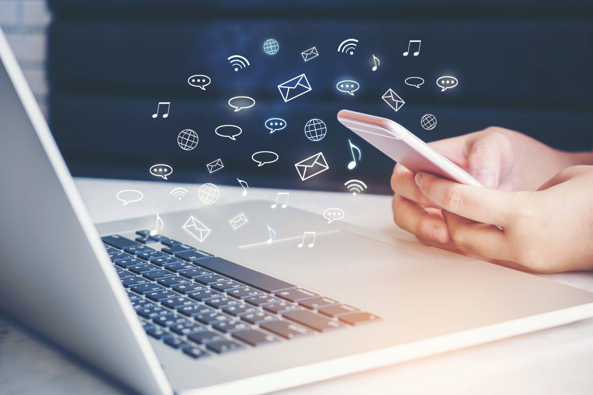Person som använder mobil vid en laptop, med digitala ikoner som symboliserar meddelanden och nätverkskommunikation.
